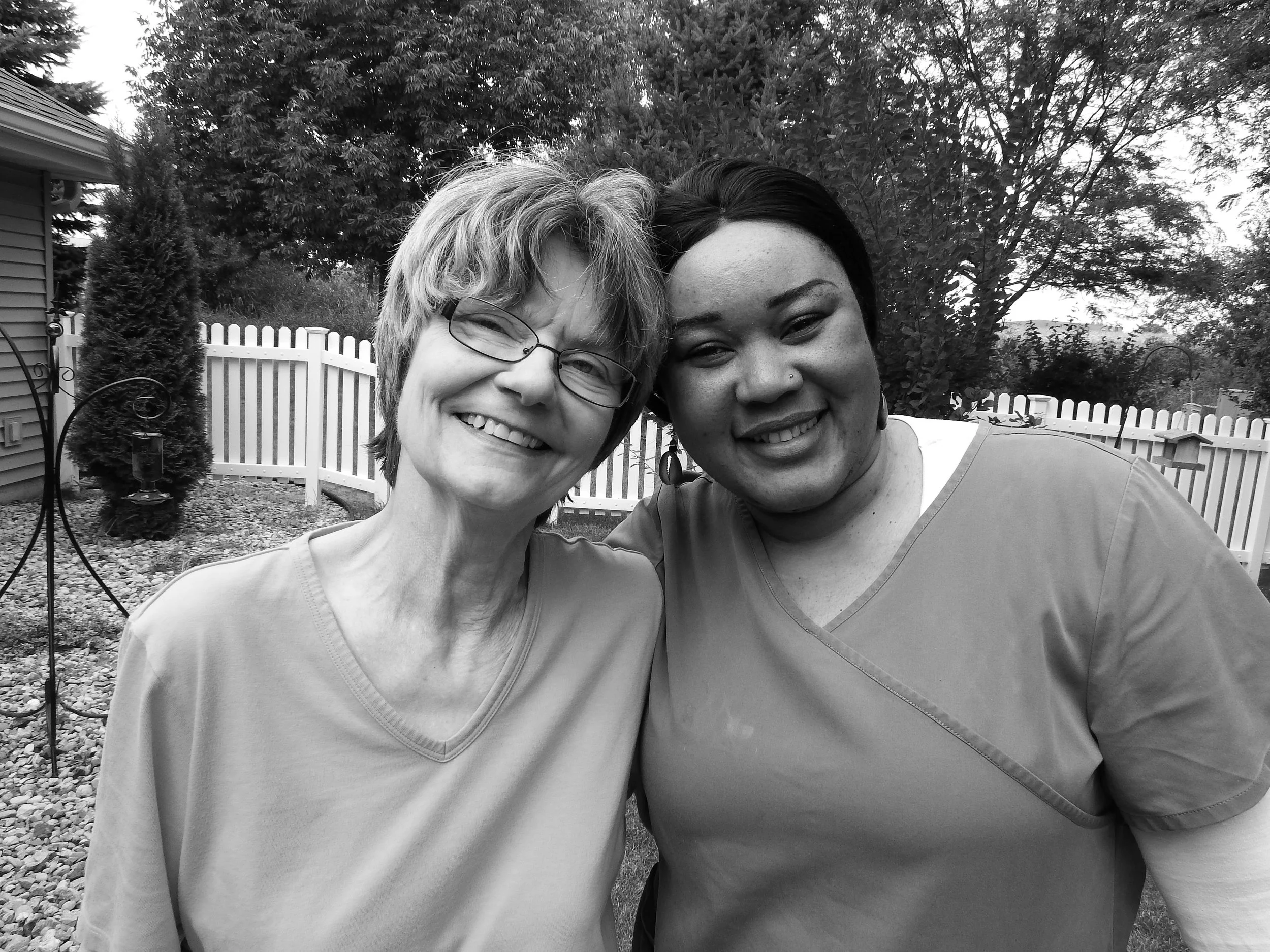Resident and caregiver smiling together outdoors